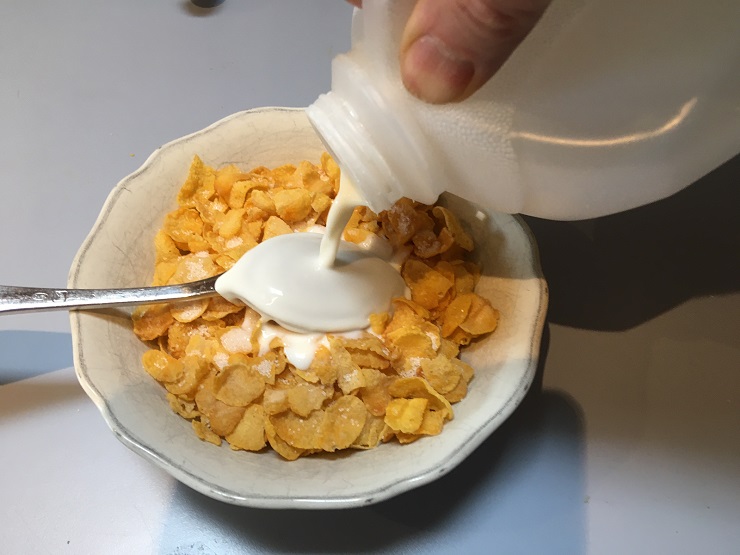 Pouring milk over upturned spoon on cereal